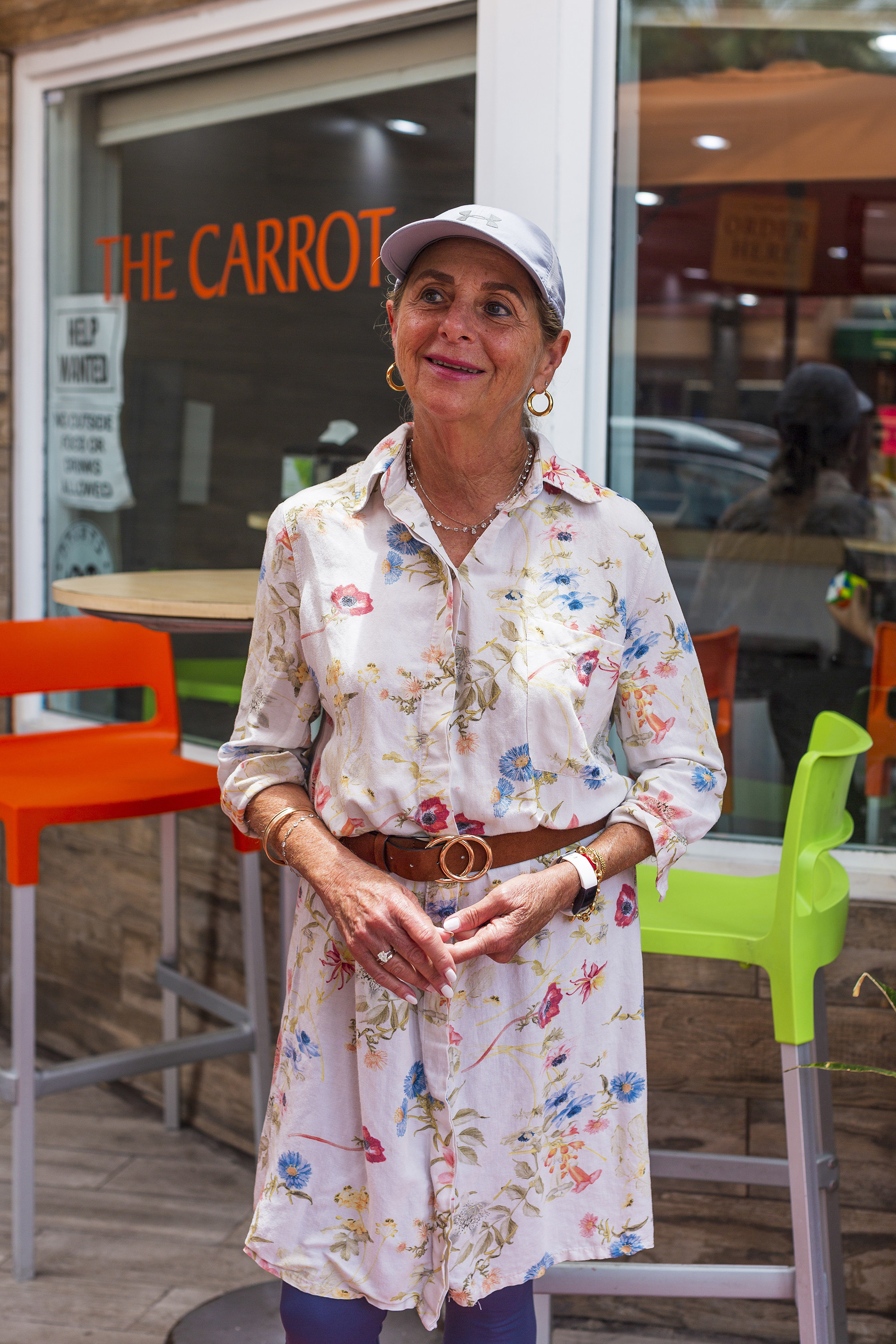A woman in a floral dress stands outside her business