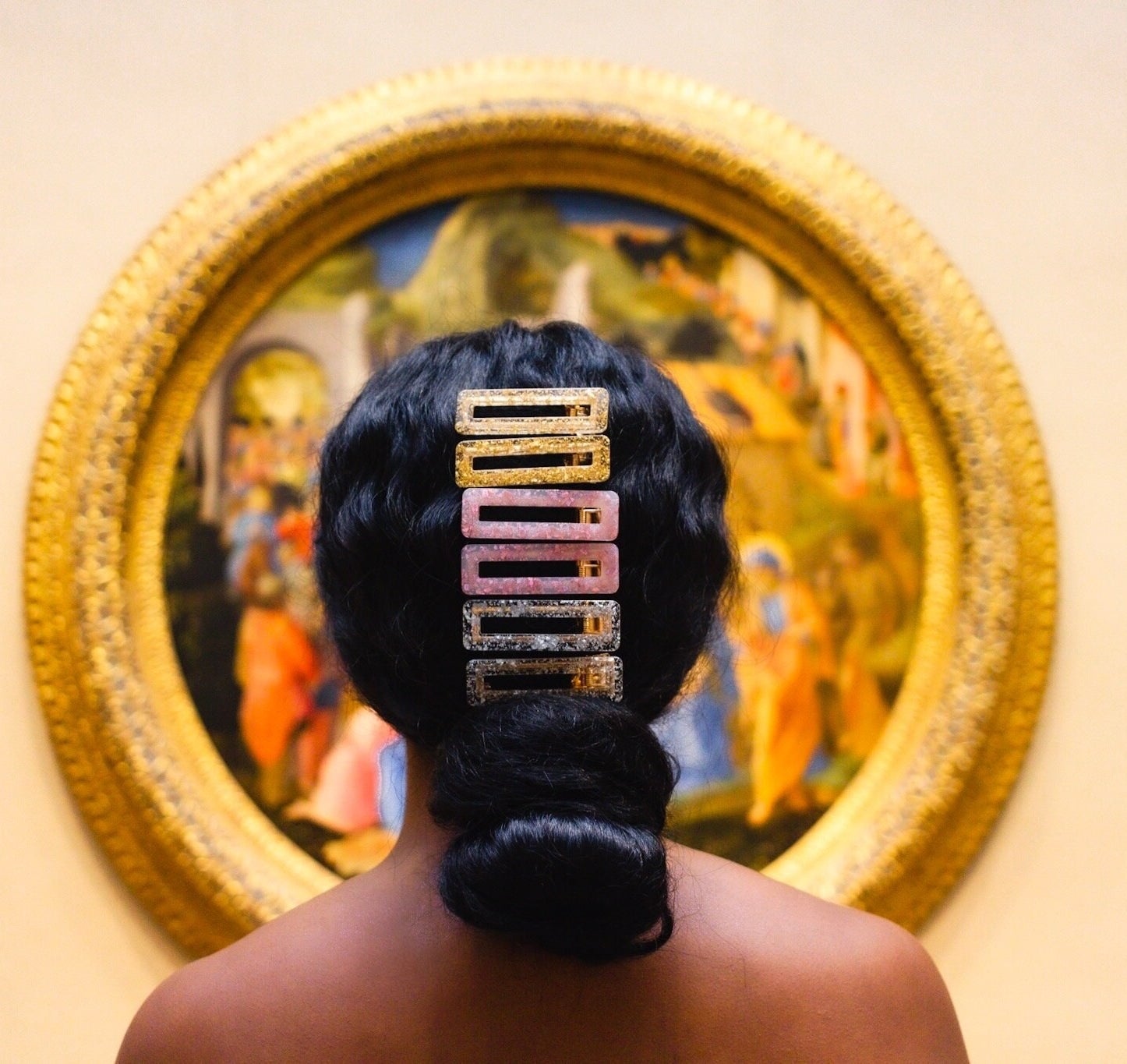 model wears multi-colored glittery hair clips in hair above low bun