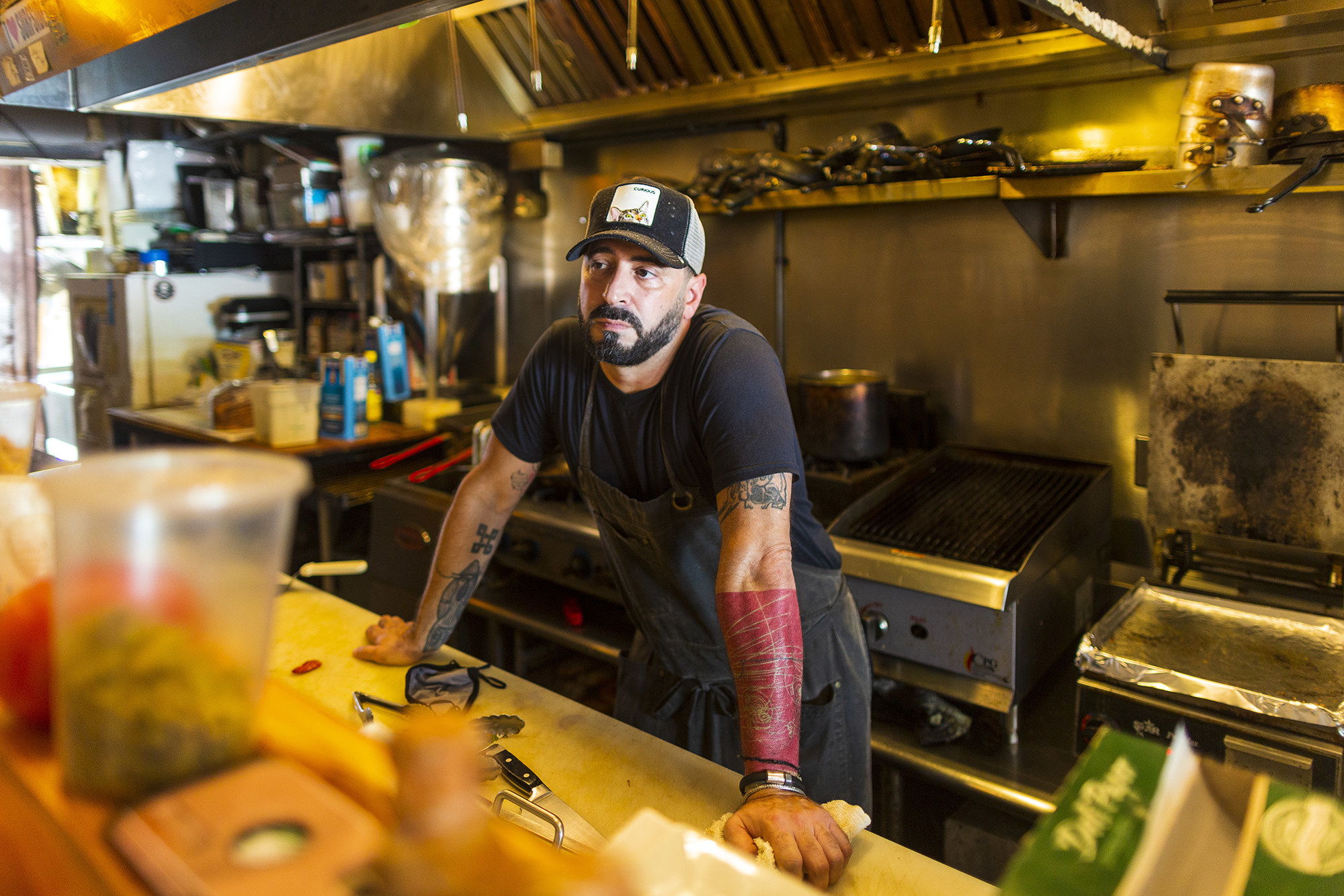 A man leans on a kitchen counter in front of a grill, looking sad