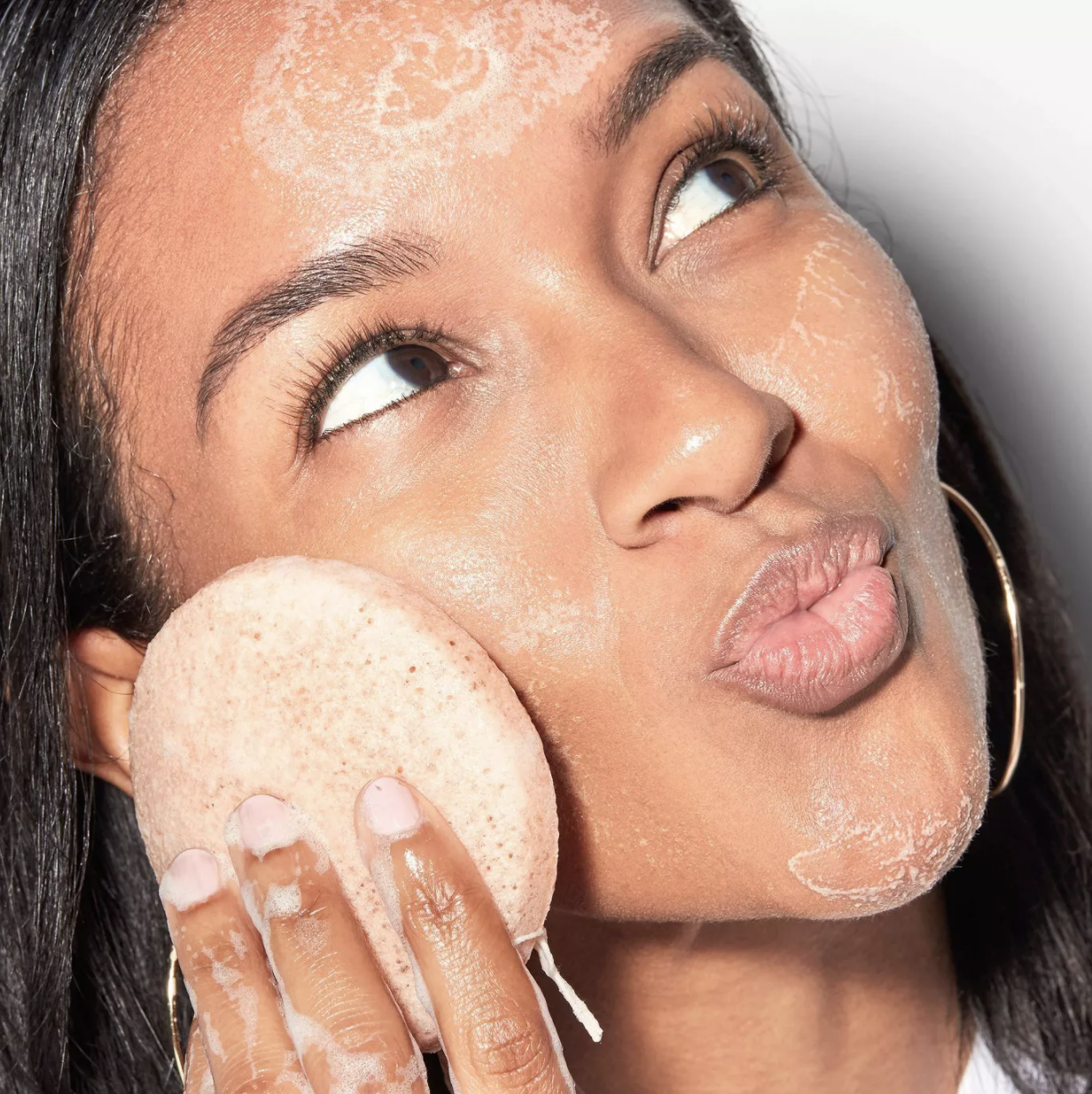 Model rubs konjac sponge onto cheek while washing face