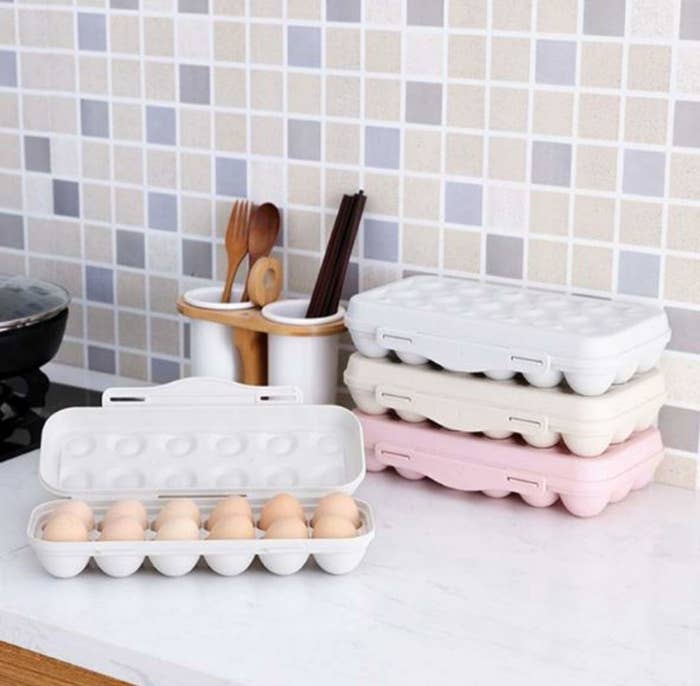Grey, beige and pink egg holders with eggs on kitchen slab