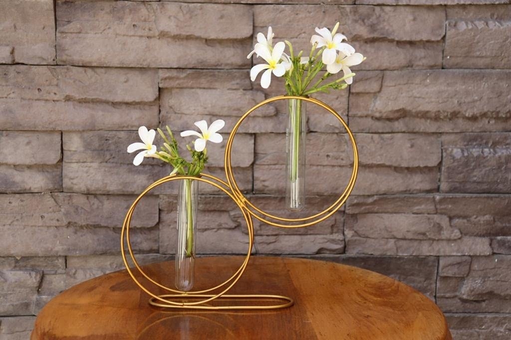 Two circular golden vases with 2 plants in them