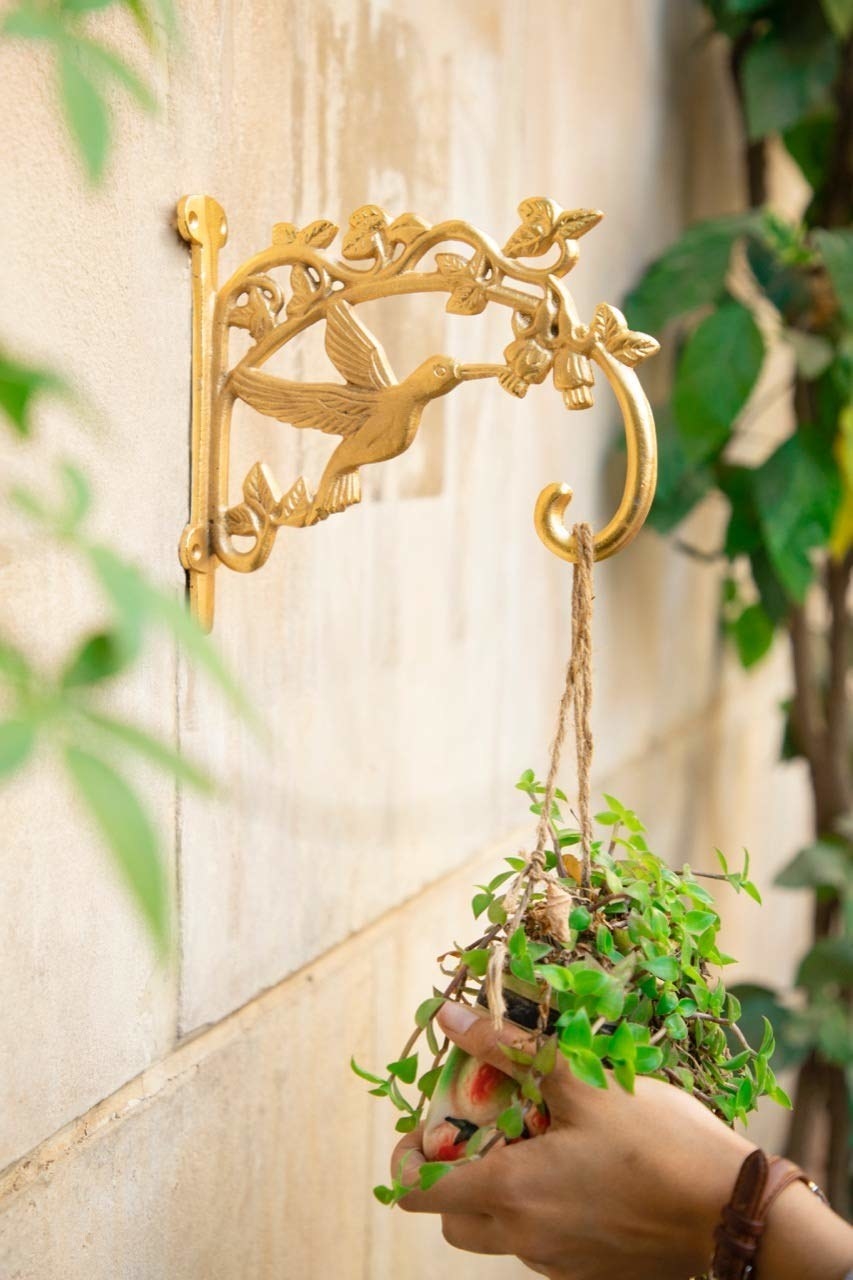 A golden bird bracket with a person holding a plant underneath it