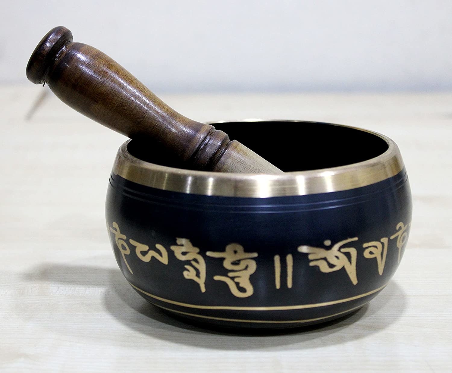 A blue and gold Tibetan singing bowl with a golden mallet