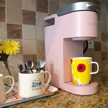 a reviewer photo of a slim pink Keurig machine with a mug sitting on the bottom tray 