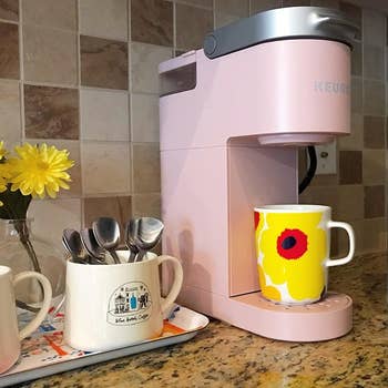 a reviewer photo of a slim pink Keurig machine with a mug sitting on the bottom tray 