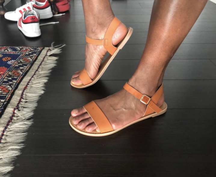 reviewer wearing flat sandals with strap across toes and ankle strap
