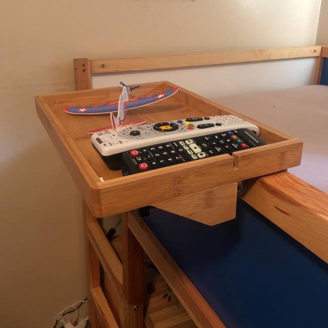 a reviewer photo of the shelf attached to the frame of an upper bunk bed 