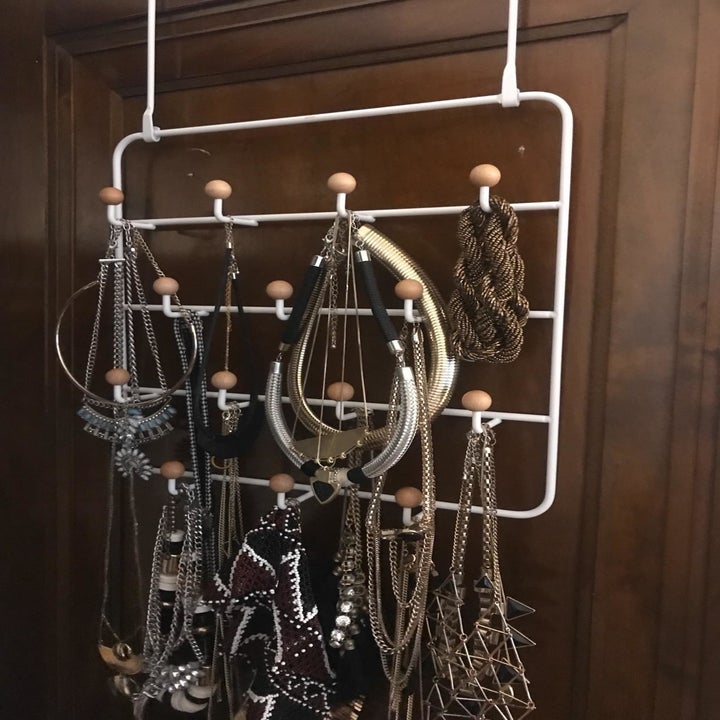 reviewer image of chunky bracelets and necklaces hanging from the umbra over-the-door organizer