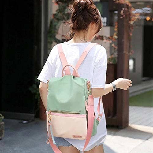 A woman wearing a half pink and half green pastel backpack
