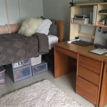 a reviewer photo of a dorm bed on risers with storage tubs underneath 