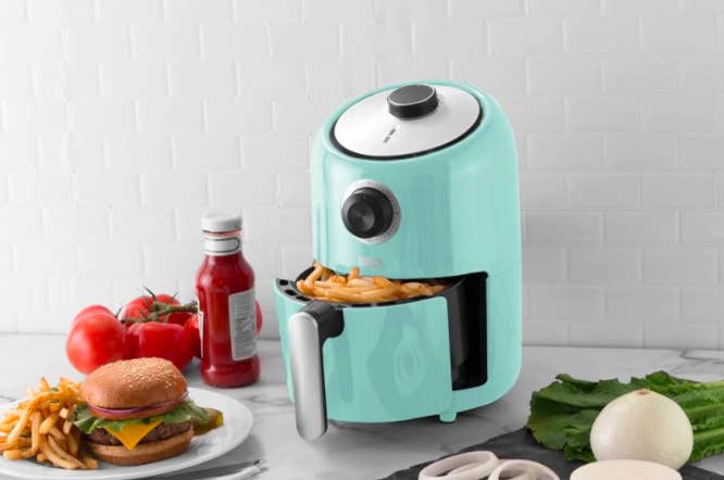 A brightly coloured air fryer filled with fresh french fries