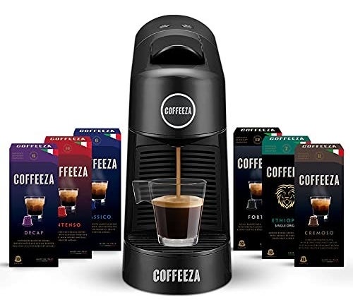 A Coffeeza Finero machine next to multiple coffee bean capsule packs such as Decaf, Classico, and Cremoso, among others