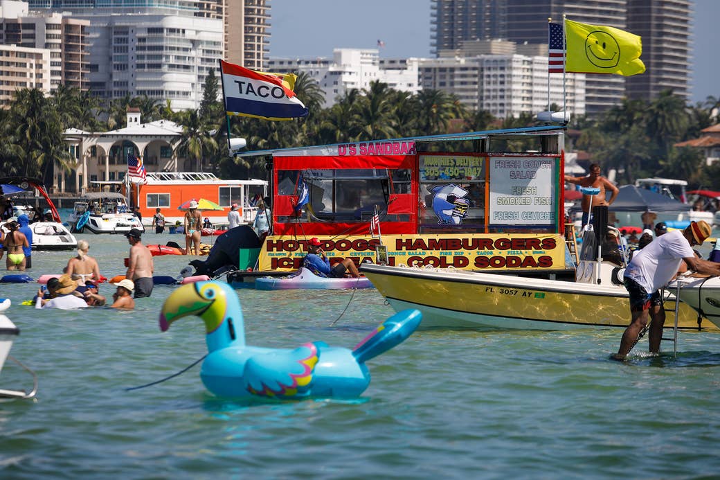 A floating group of boats with the Miami skyline in the background 