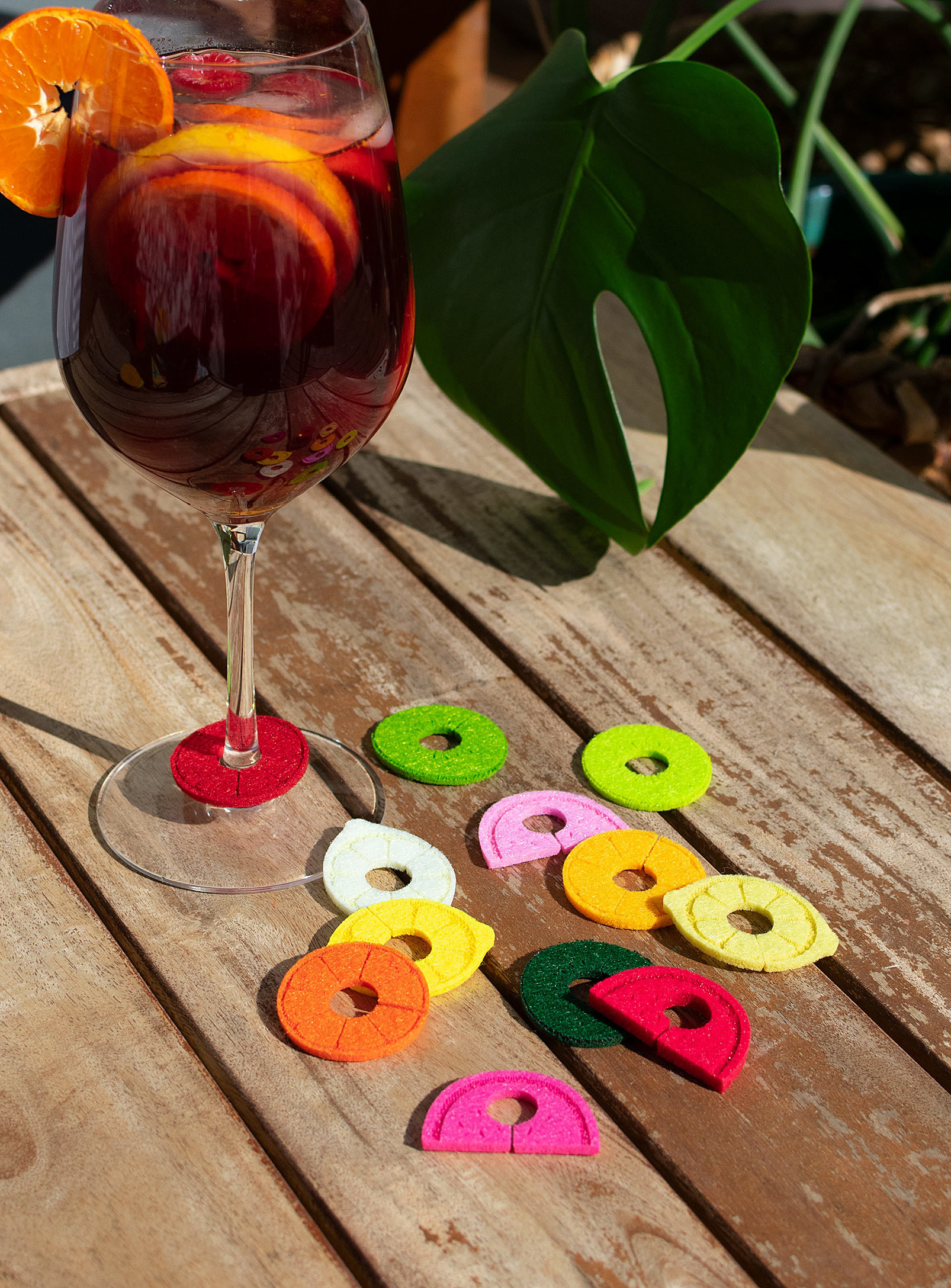 A set of felt fruit-shaped drink markers next to a full wine glass