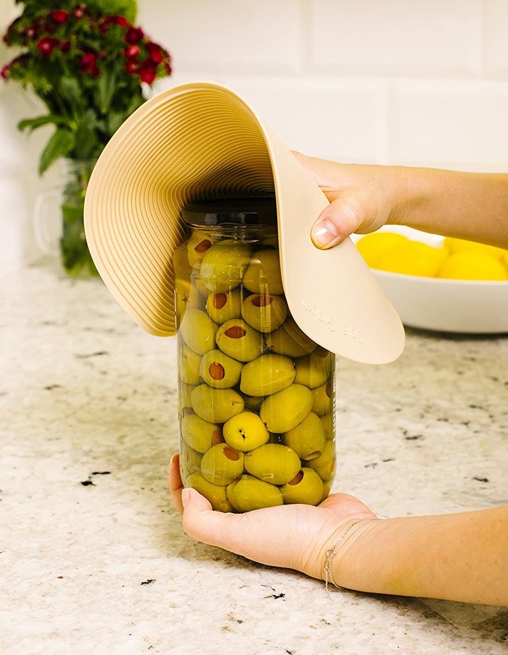 Someone using the silicone mat to open a jar of olives
