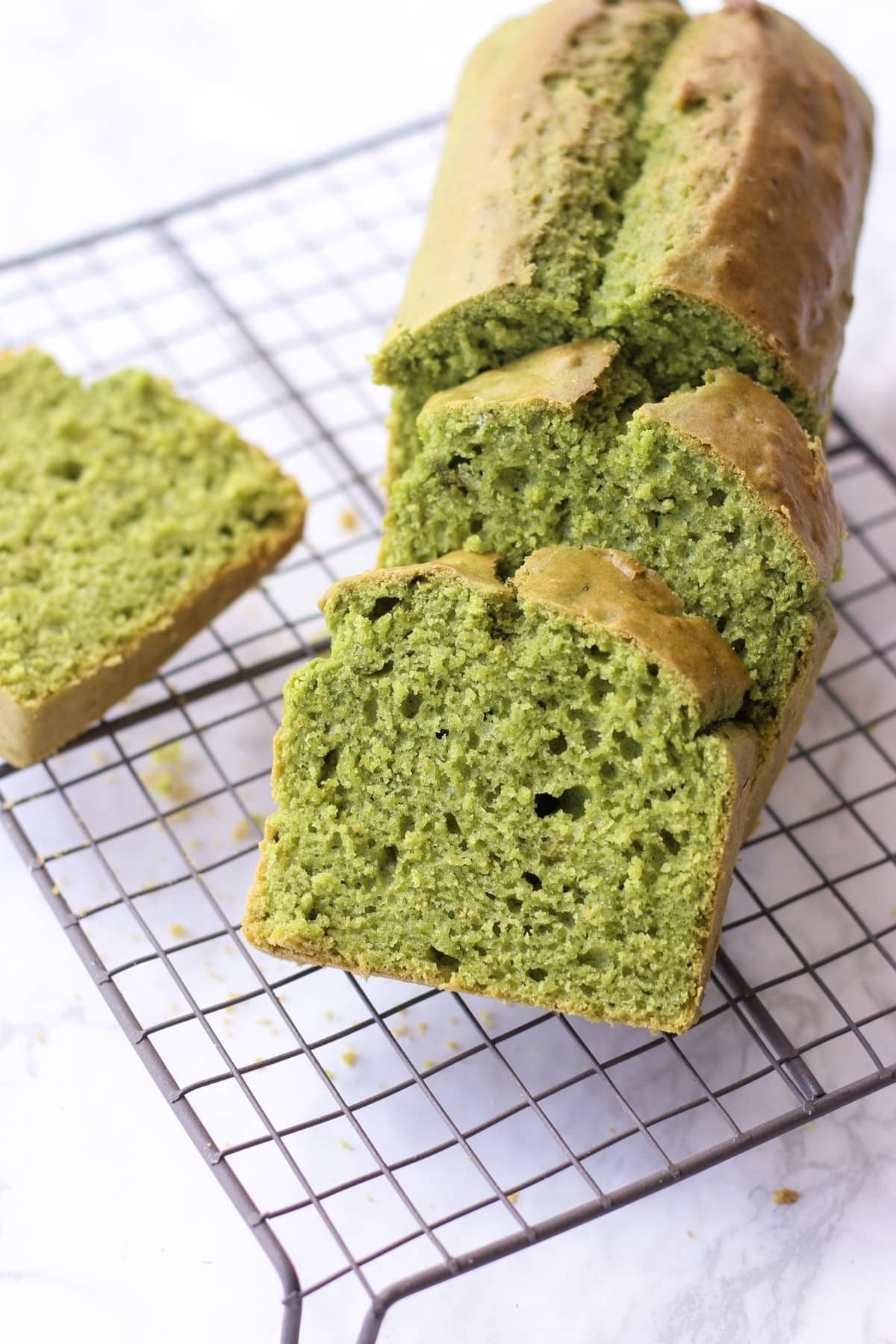 Slices of matcha pound cake laying on top of wire cooling rack.