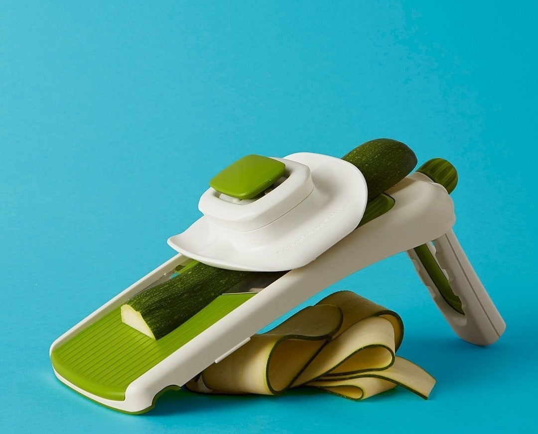 A collapsible mandoline with a half-shaved zucchini on tp