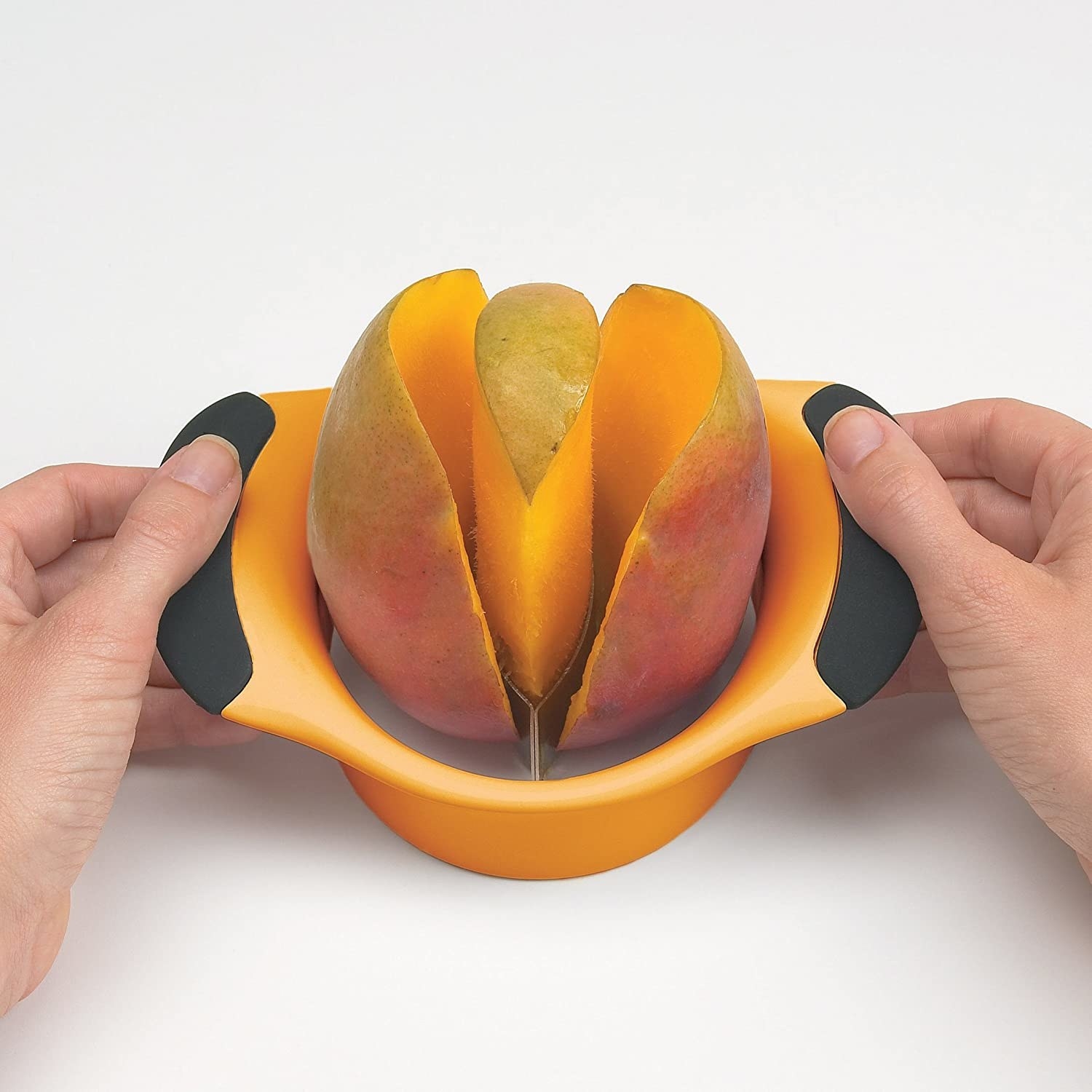 Someone using the mango slicer to pit a fresh mango
