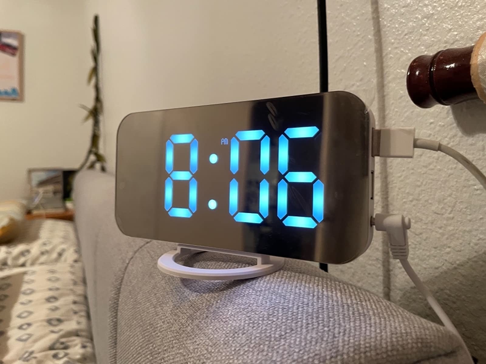 Reviewer photo of the digital clock on top of a couch, with blue LED lit numbers