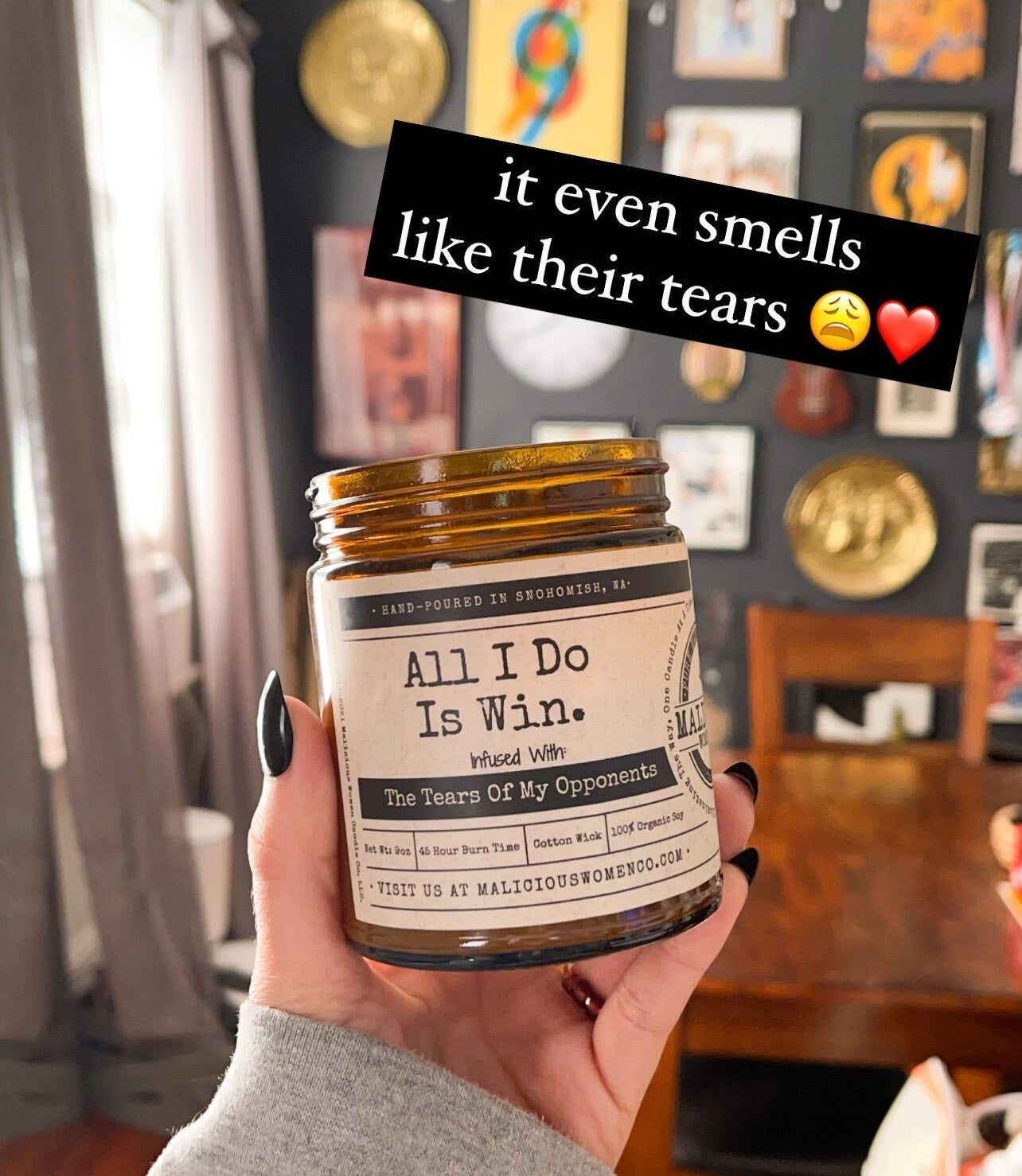 A person holding up a candle that says &quot;All I do is win, infused with the tears of my opponents&quot; and the words &quot;it even smells like their tears&quot; written on the image
