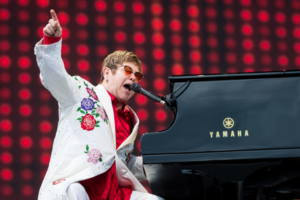 Elton John plays a piano and sings