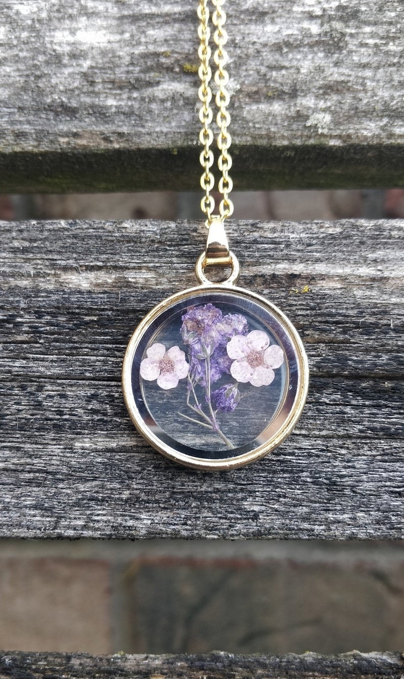 a dried lavender encased in glass on a gold chain