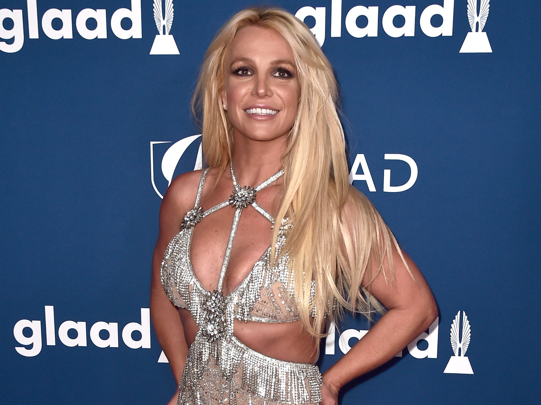 Britney smiles while wearing a cutout dress with diamond fringe