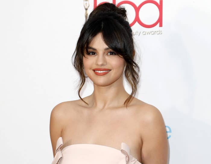 Selena smiles with her hair pulled back and a blush colored strapless dress