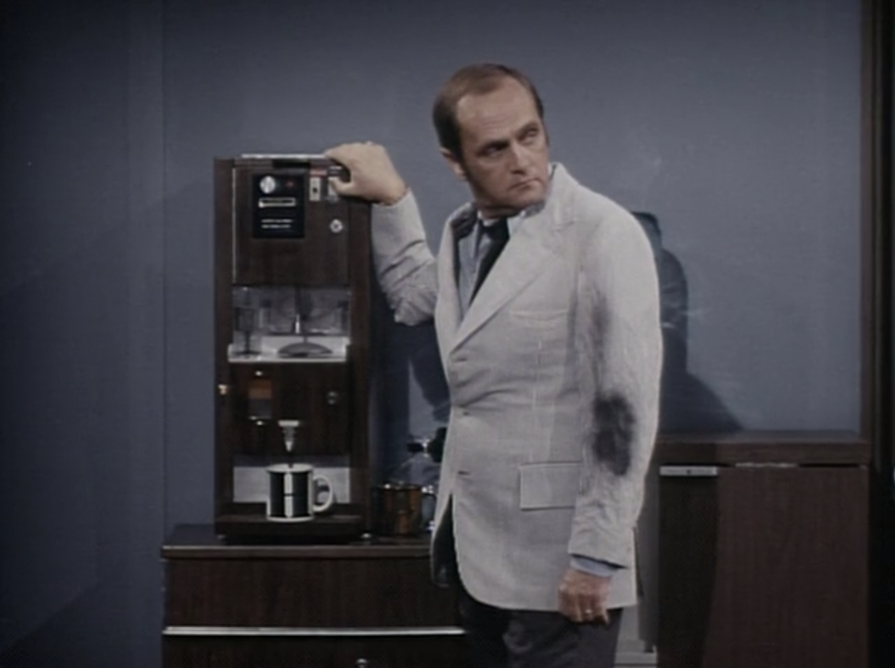 Bob Newhart standing in front of a coffee machine as Dr. Robert Hartley