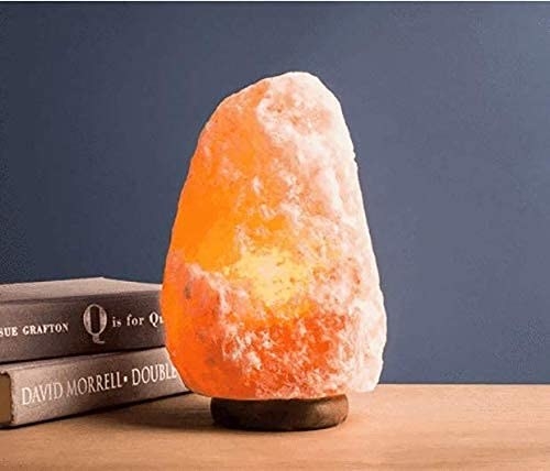 A Himalyan salt lamp on a table with books