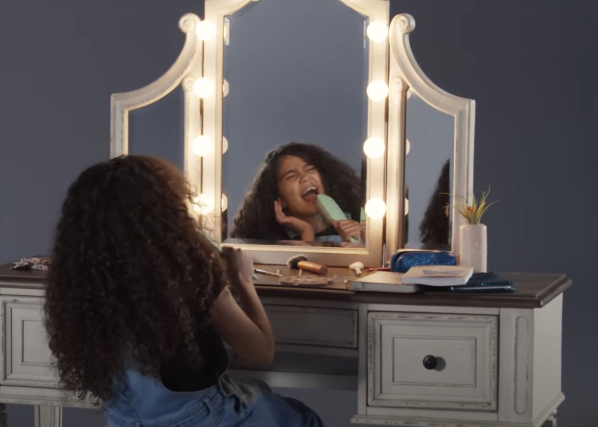 Monroe sings into a hairbrush while sitting in front of a vanity