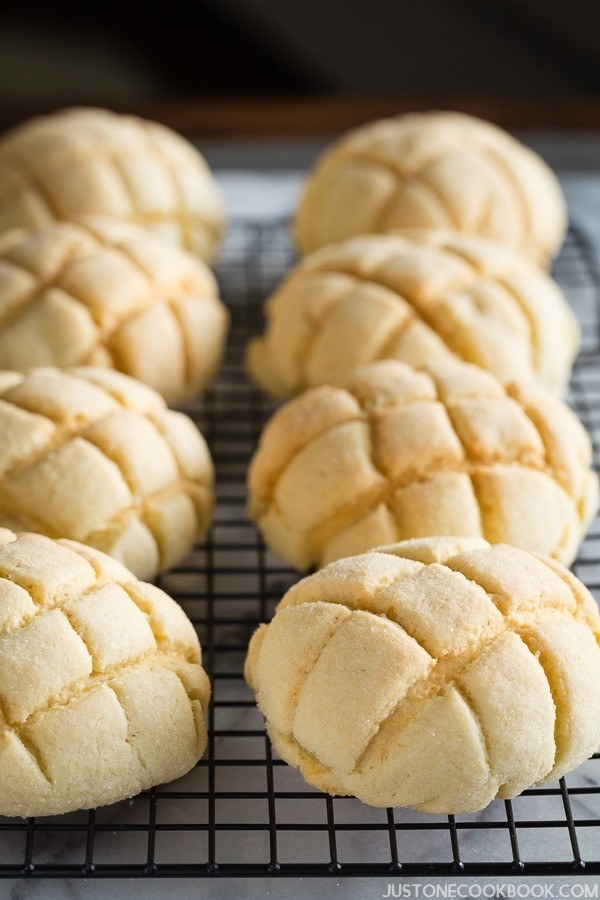 Loaves of melon bread textured with a criss-cross pattern laying on a cooling rack.