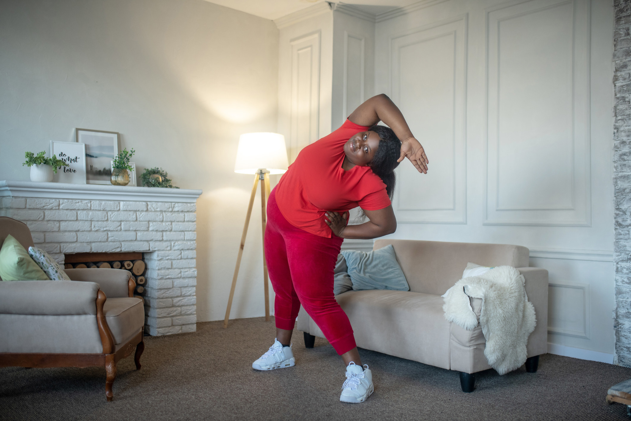a woman stretching over her head in her living room