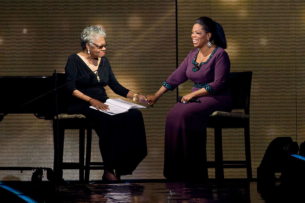 Maya Angelou and Oprah hold hands onstage