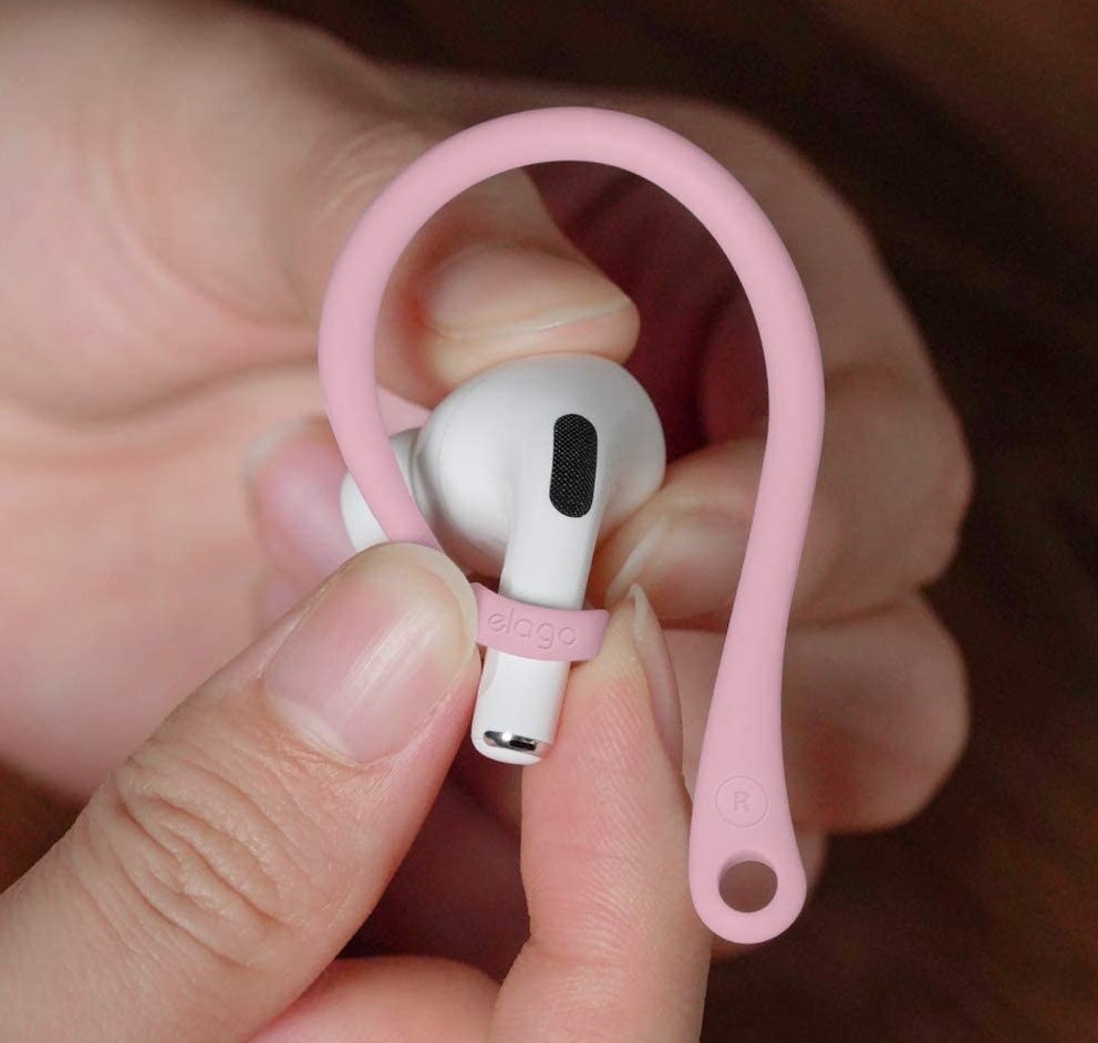 A person holding an AirPod with the hook on it
