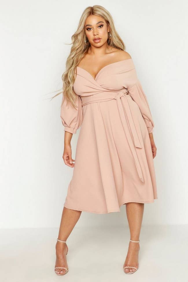 a model in the pale pink off the shoulder wrap dress
