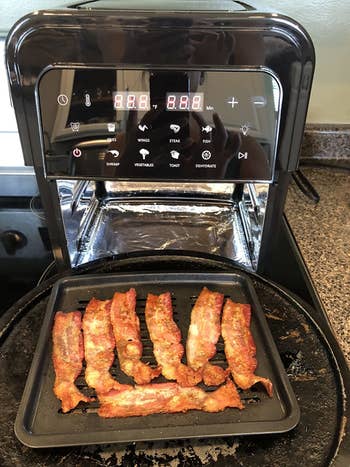 the same air fryer open to reveal cooked bacon