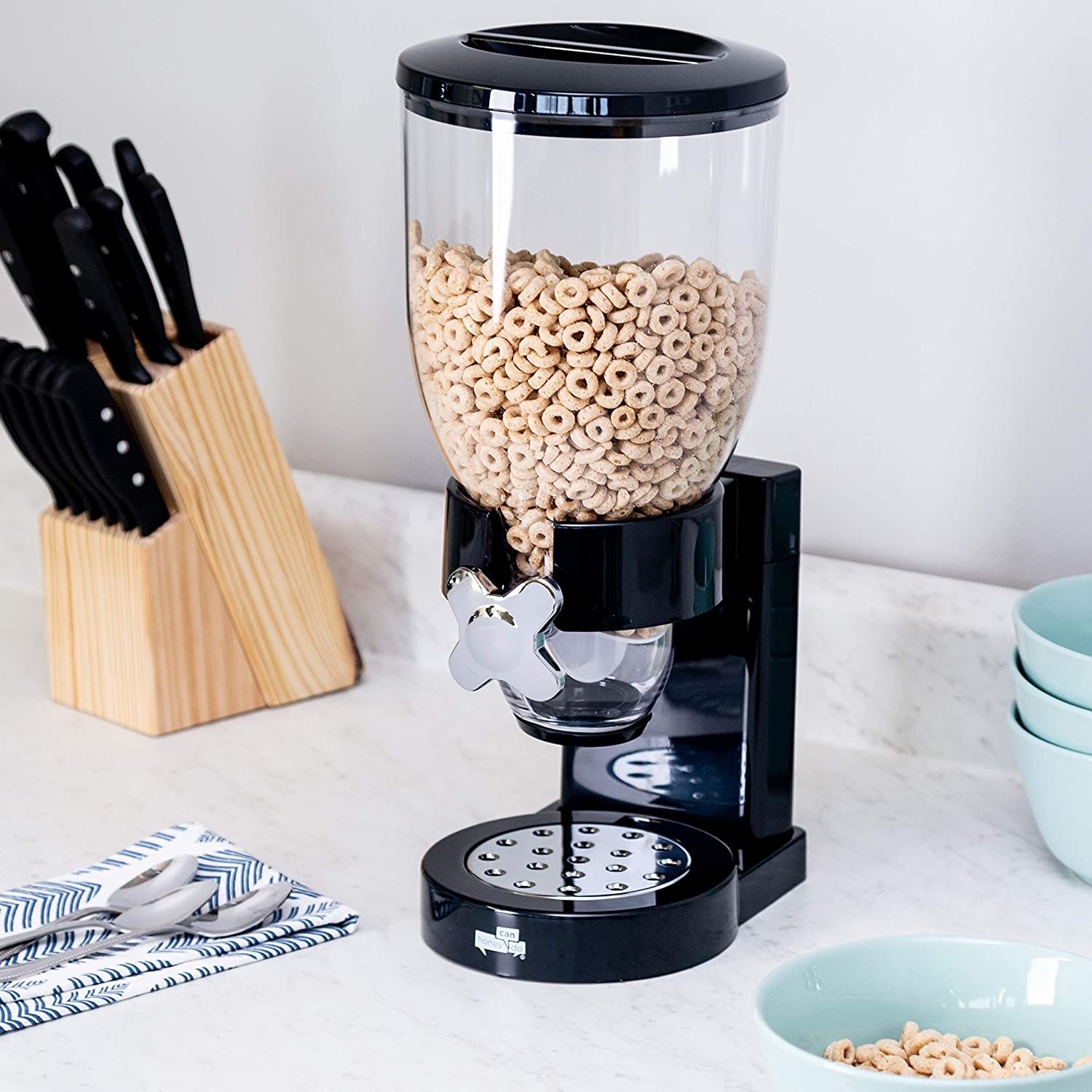 The cereal dispenser on a counter filled with Cheerios