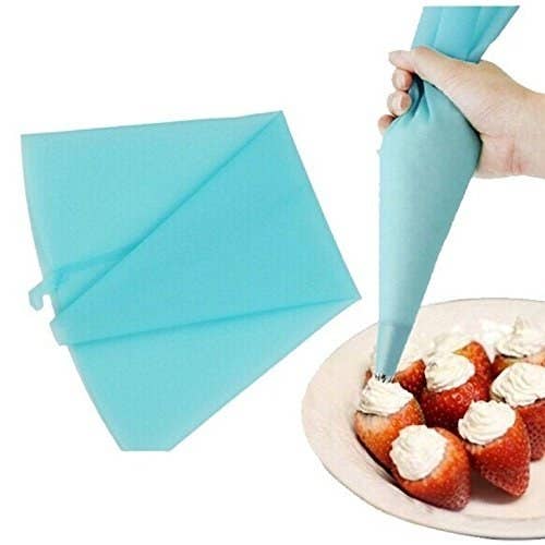 A person using the piping bag to add cream to straberries