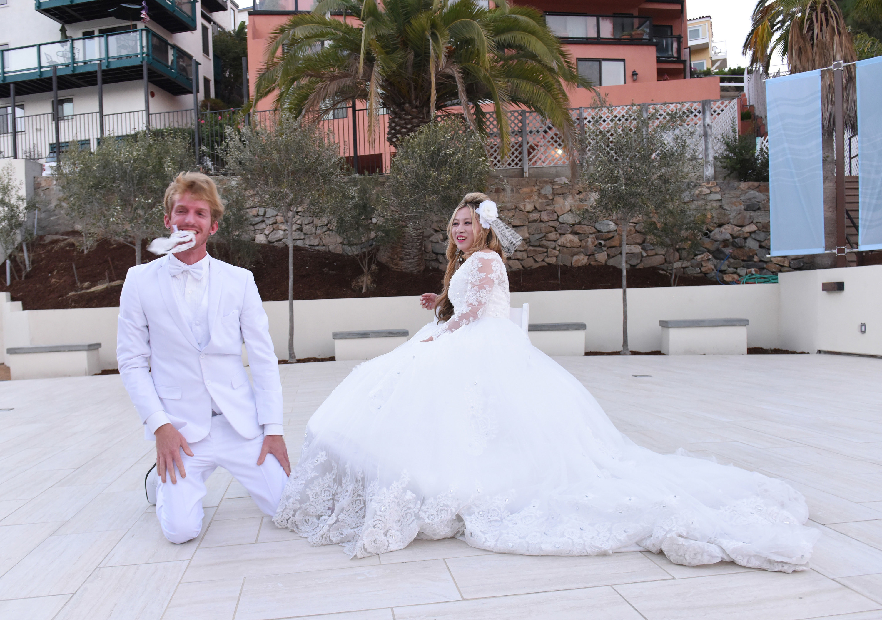 A groom holding his bride&#x27;s garter in his mouth as she looks on