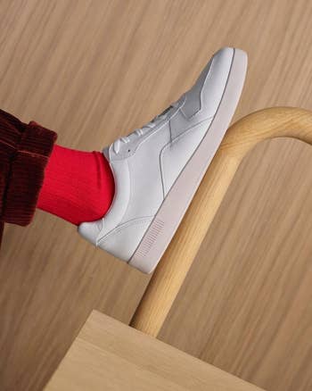 lifestyle photo of a foot wearing red sock and the white sneaker