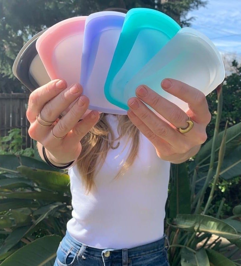 A person holding several colours of the silicone baggies in front of their face