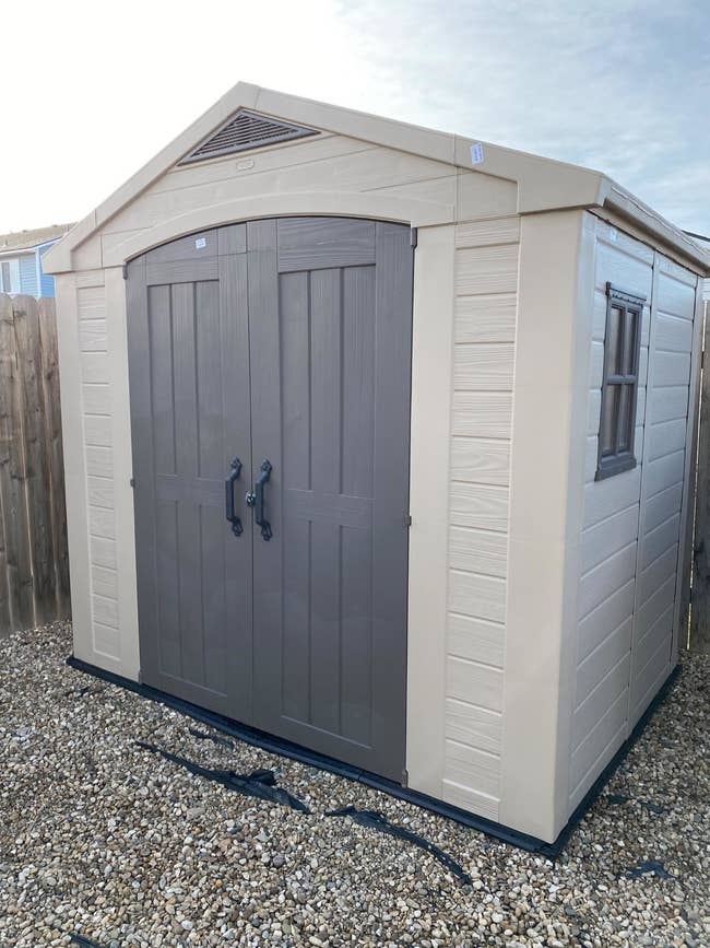 the outdoor shed with double doors and a shingle roof