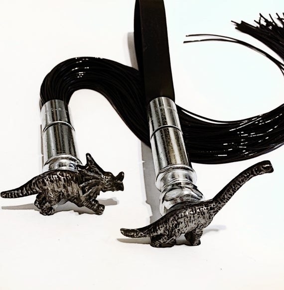 Silvertone and black flogger with triceratops handle and second paddle with brachiosaurus handle