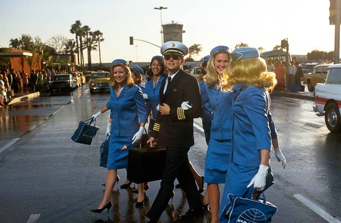 Leo's character crossing the street with flight attendants on his arms