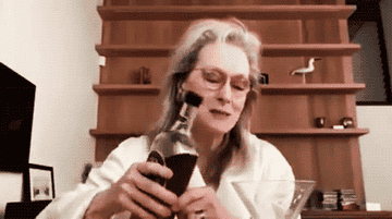 Meryl Streep holding a bottle of alcohol and drinking from it