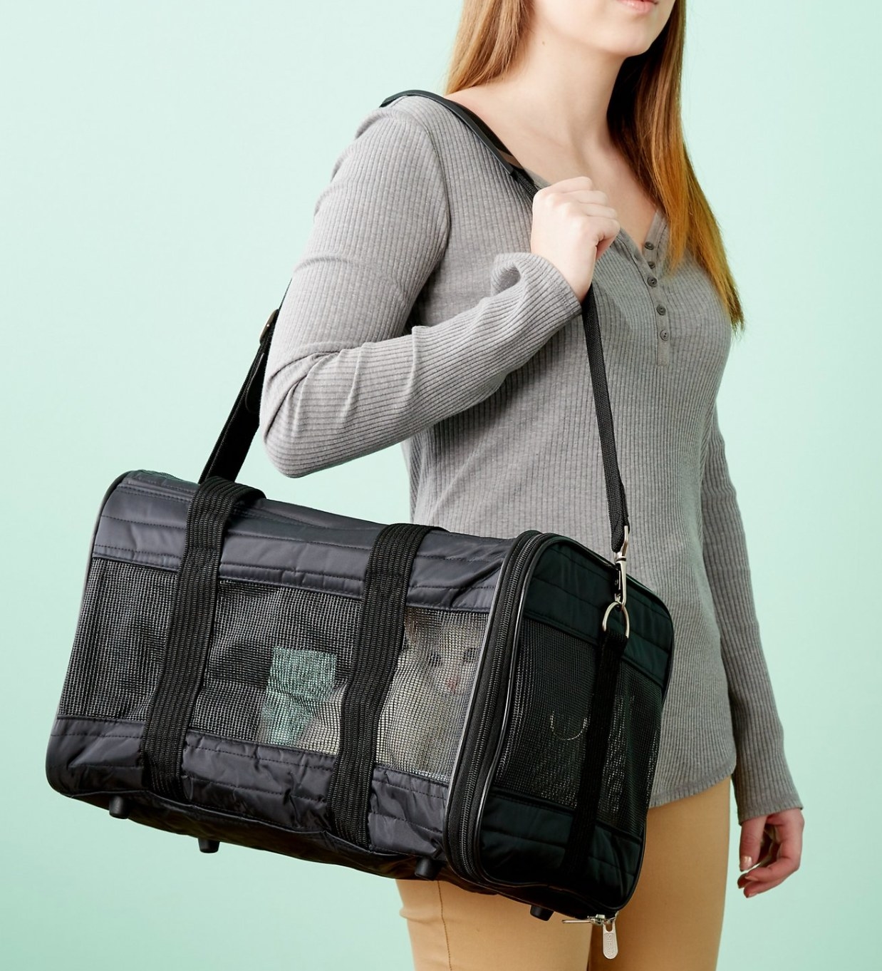 woman holding a travel pet bag with a cat