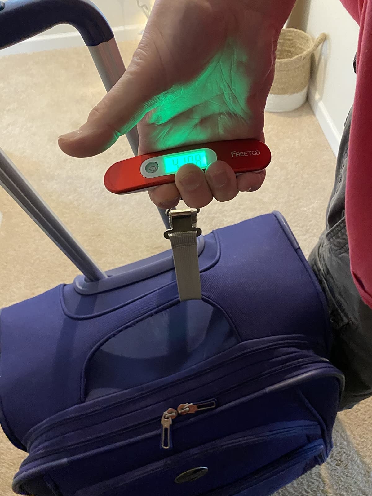 reviewer using the luggage scale to weight their suitcase