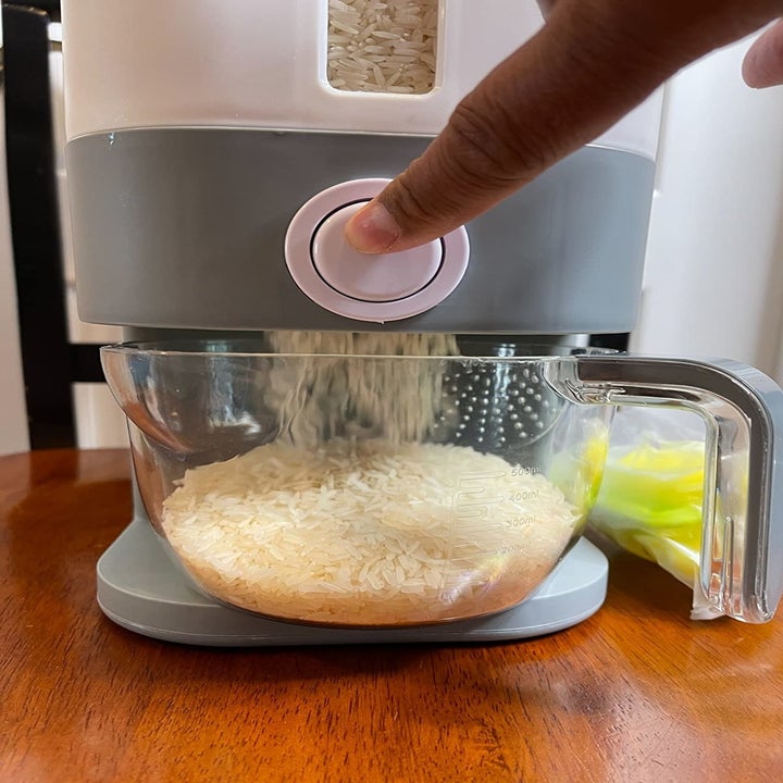 image of reviewer pressing the rice dispenser button, thereby dispensing rice into a measuring cup